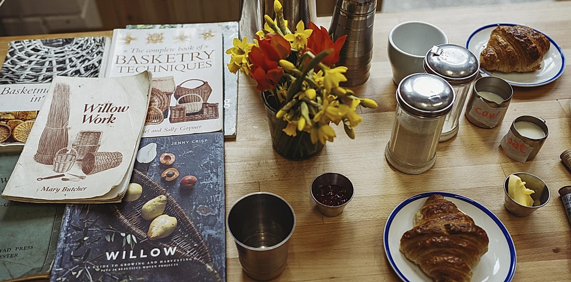 Table scape of books around weaving and pastries