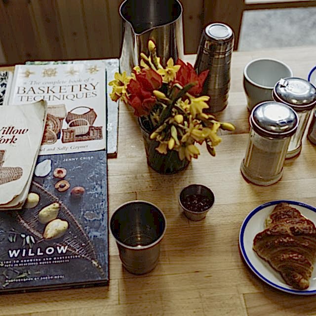 Table scape of books around weaving and pastries