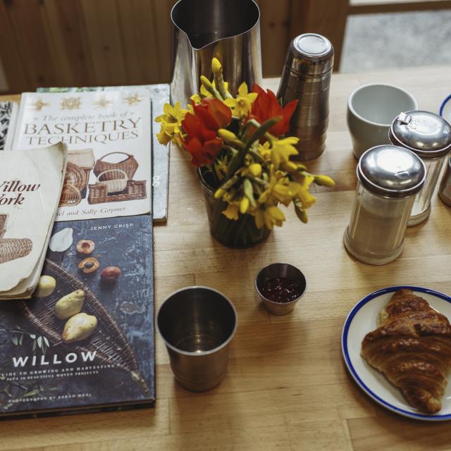 Table scape of books around weaving and pastries